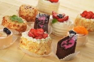 16279231-small-cakes-with-cream-and-berries-on-bamboo-table-cloth