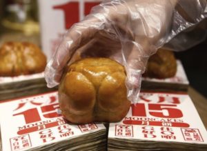 A sales assistant presents a buttock-shaped mooncake sold ahead of the Mid-Autumn festival in Singapore