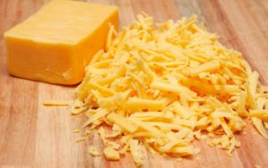 Grated mature cheddar cheese on wooden board